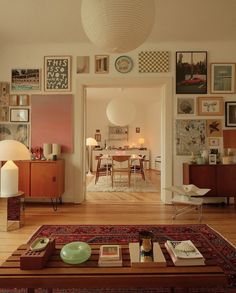 a living room filled with lots of furniture and pictures on the wall next to a coffee table