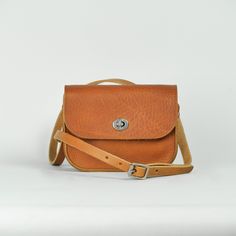 Our classic small cross body bag, crafted using rustic matte Tan leather. We love this small satchel style, and wanted to create a softer version, using the same supple, study, vegetable tanned leather which we use for our belts.  Measuring 19 x 15 x 5 cm, and with a strap adjustable between 128 and 137 cm, the vegetable tanning process beautifully preserves the organic past life of the material, creating a natural, characterful, finish, which will wear beautifully, taking on personality and charm with use.  Completed with a silver finish turnlock closure for accessibility and security, the minimal design aims to be an easy every day accessory. Always lovingly handmade in our London workshop.  Recently we have created a small run of accessories using the robust Italian vegetable tanned lea Classic Everyday Crossbody Saddle Bag, Everyday Saddle Flap Bag With Adjustable Strap, Classic Saddle Shoulder Bag For Everyday, Classic Crossbody Shoulder Bag With Leather Strap, Classic Saddle Flap Bag For Everyday Use, Classic Leather Strap Crossbody Shoulder Bag, Everyday Use Saddle Flap Bag With Adjustable Strap, Everyday Soft Leather Saddle Bag, Classic Saddle Bag With Leather Strap For Daily Use