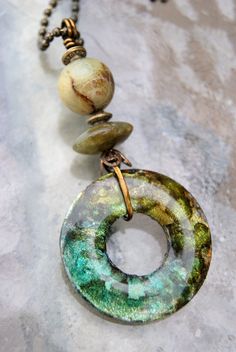 a green and white necklace on a chain with two bead charms hanging from it