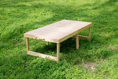 a wooden table sitting on top of a lush green field