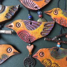 a group of colorful birds hanging on a wall next to each other with beaded necklaces around them