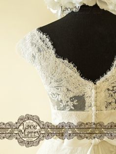 the back of a wedding dress with white lace and ruffled trims on it