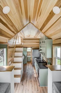 the interior of a tiny house with wood floors and white walls, stairs leading up to an upper level kitchen