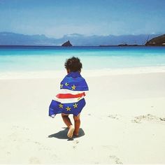 a little boy walking on the beach with a towel wrapped around his body