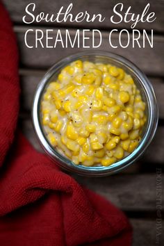 a bowl filled with corn sitting on top of a wooden table next to a red towel