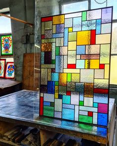 a colorful glass window sitting on top of a metal table in front of some windows