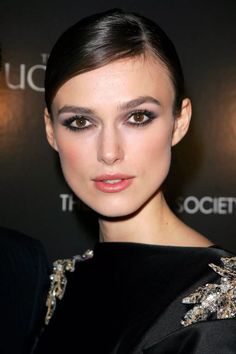 a woman with dark hair wearing a black dress and silver eyeliners is posing for the camera