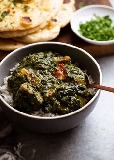 a bowl filled with rice and spinach next to pita bread on a cutting board