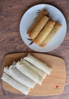 some food is sitting on a wooden cutting board next to a white plate and knife