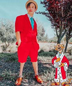 a young man in a red suit and hat standing next to a tree with a cartoon character on it