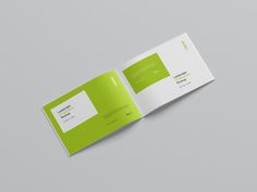 a green and white brochure is open on the gray surface, revealing an image of a business card