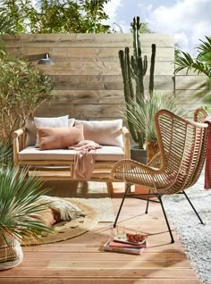 an outdoor living room with plants and furniture in the foreground, along with a wooden wall