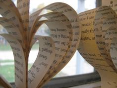 two hearts made out of book pages sitting on top of a window sill