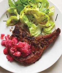 a plate with meat, lettuce and cranberry sauce on it sitting on a table