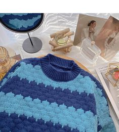 a blue and white sweater sitting on top of a table next to other items in front of a mirror