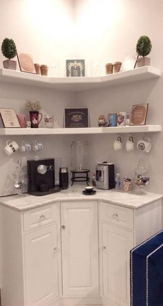 a kitchen with white cabinets and shelves filled with items