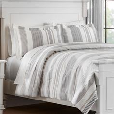 a white bed with striped comforter and pillows