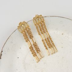 These MALENA SHORT Fringe Drop Earrings will add playful charm to any look. These earrings are designed to make a classy statement no matter the occasion. The fringe design adds movement and fun. You're sure to be noticed when wearing these earrings. Features: Comfortable Lightweight Super elegant High quality Hypoallergenic Drop design Size & Material: Length: 1.5" long. Material: 14K gold plated, 14K gold filled post and backing. Chic Metal Dangle Tassel Earrings, Chic Metal Tassel Dangle Earrings, Party Tassel Dangle Earrings With Dangling Charms, Gold Plated Dangle Chandelier Earrings For Party, Gold Plated Chandelier Dangle Earrings For Parties, Gold Plated Chandelier Earrings For Party, Metal Fringe Dangle Earrings, Fringe Dangle Metal Earrings, Party Tassel Drop Earrings With Dangling Charms