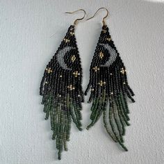 two pairs of beaded earrings with green and black beads on white fabric, one has an eye in the middle