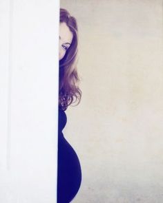 a pregnant woman leaning against a wall