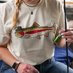 Saddle up and head to the lake with this cowboy trout tee!  If you're looking for a thick, structured tee that's also super soft and breathable--look no further! The Comfort Colors unisex garment-dyed heavyweight t-shirt ticks all the boxes and is made of 100% ring-spun cotton. The regular t-shirt style will complement most looks and fit you to a tee. * 100% ring-spun cotton * Fabric weight: 6.1 oz/yd² (206.8 g/m²) * Garment-dyed * Relaxed fit * 7/8″ double-needle topstitched collar * Twill-taped neck and shoulders for extra durability * Double-needle armhole, sleeve, and bottom hems * Blank product sourced from Honduras This product is made especially for you as soon as you place an order, which is why it takes us a bit longer to deliver it to you. Making products on demand instead of in Country Tee Shirts, Fisherman Aesthetic, Lake Fashion, Fisherman Outfit, Fish T Shirt, Fisherman Style, Fish Shirt, Chapeau Cowboy, Cow Boy