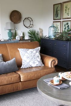 a brown leather couch sitting in a living room next to a table with food on it