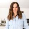 a woman standing in a kitchen with her hands on her hips and looking at the camera