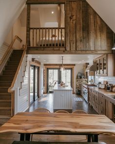 a wooden table sitting in the middle of a kitchen next to a stairway leading up to a loft