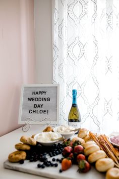 a table topped with bread and fruit next to a sign that says happy wedding day gloee