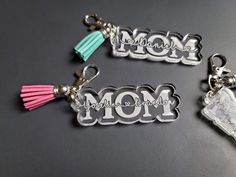 three keychains with the word mom written in silver and pink tassels