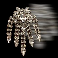 "It can not but be a good day when you are wearing this magnificent diamantè brooch characterized by a clear persuasive light! Its big fringe design is studded with clear round, drop, oval and marquise rhinestones, in various sizes, prong set on silver rhodium tone It has a rich upper part, almost a motif of leaves where in the center stands a large faceted rhinestone oval, from which there are 5 dangling double lines of rhinestones that end with a dazzling drop The brooch is dated 1950s, in Old Glamorous Party Brooch Jewelry, Glamorous Formal Brooches With Bling, Formal Crystal Brooches With Rhinestones, Formal Crystal Rhinestone Brooches, Glamorous Formal Brooches With Rhinestones, Silver Crystal Brooch With Sparkling Stones, Silver Crystal Brooches With Sparkling Stones, Party Crystal Brooch Jewelry, Glamorous Crystal Brooches For Formal Occasions