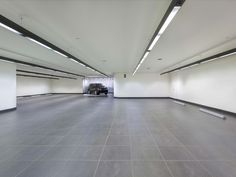 an empty parking garage with white walls and grey flooring is seen in this image