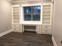 an empty room with white bookcases and wood flooring on the side wall