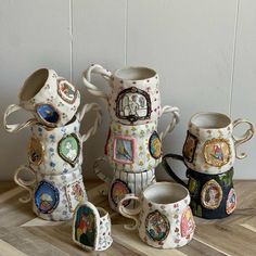 five coffee mugs with designs on them sitting on a wooden table next to each other