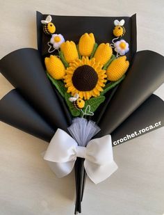 a bouquet of flowers made out of corn on the cob and black paper with white ribbon