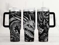 two black and white travel mugs with dragon designs on the sides, one is empty