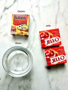 ingredients for jello sitting on a marble counter top next to a glass bowl and two packets of jello