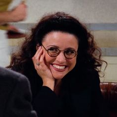 a smiling woman wearing glasses sitting next to a man in a black suit and tie