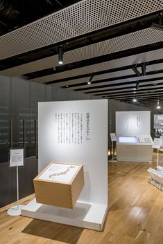 an exhibit room with white walls and wooden flooring, including boxes on pedestals