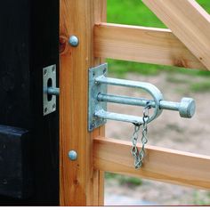 a close up of a metal latch on a wooden structure with chains hanging from it