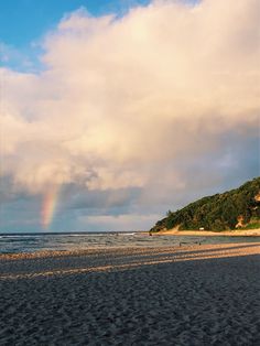 there is a rainbow in the sky over the beach