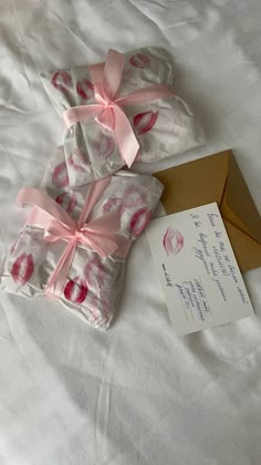 two wrapped presents sitting on top of a bed next to an envelope with a note