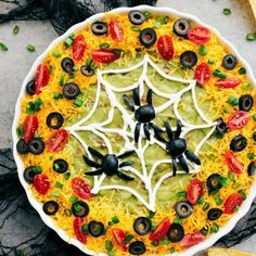 a halloween pizza decorated with black olives, tomatoes and cheese