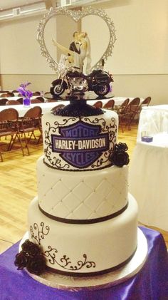 a three tiered wedding cake on top of a purple table cloth covered tablecloth