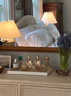 a bedroom scene with focus on the dresser and bed in the background, as well as a large mirror