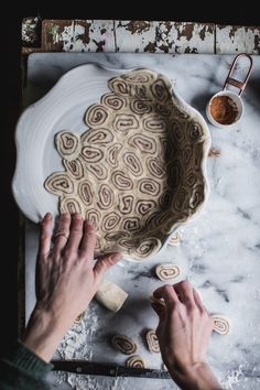 someone is making some kind of pie on a table with their hands and knifes