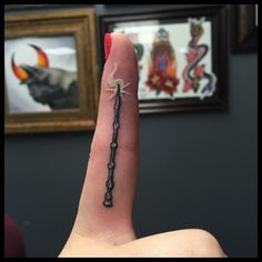 a person's finger with a tiny spider on it, in front of a painting