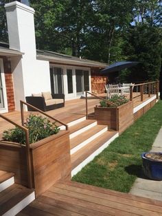 a wooden deck with planters on the side and chairs in the grass near it