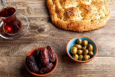 an assortment of olives, bread and tea on a wooden table