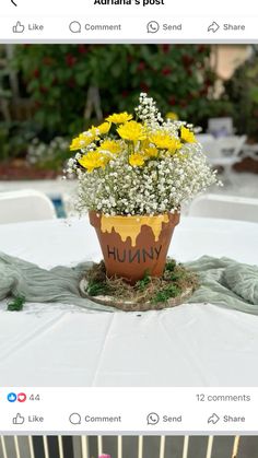 a flower pot sitting on top of a white table covered in yellow and white flowers